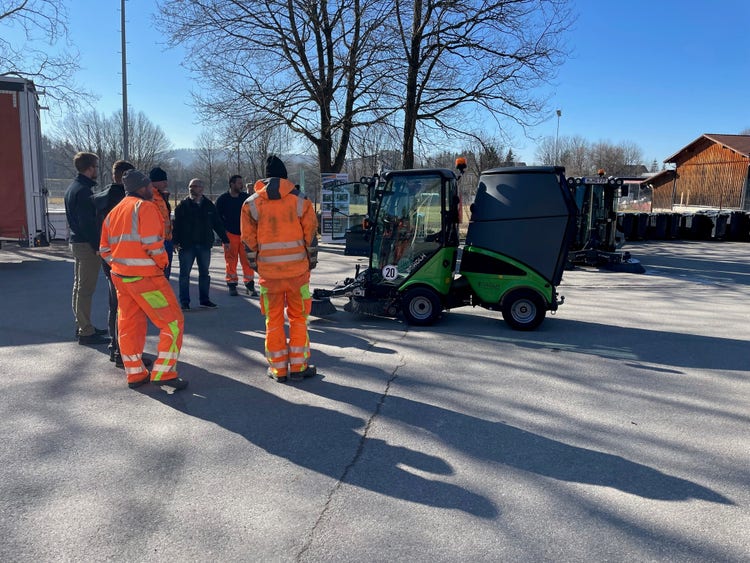 Teilnehmer in Arbeitskleidung versammeln sich um eine geöffnete Egholm Kommunalmaschine