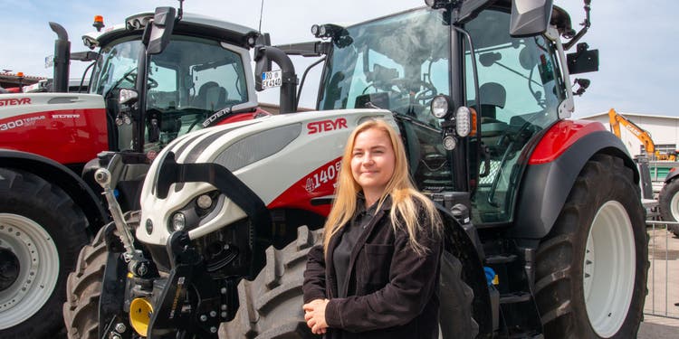 Theresa EDER steht vor einem Steyr Traktor aud dem Firmen gelände