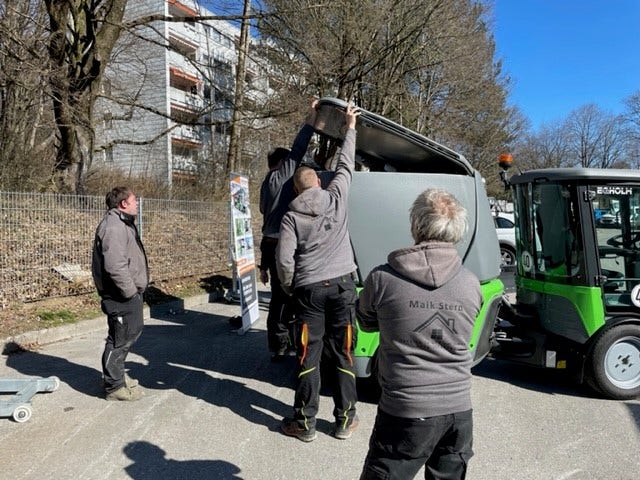 Mehrere Personen begutachten den geöffneten Sammelbehälter einer Egholm Kommunalmaschine