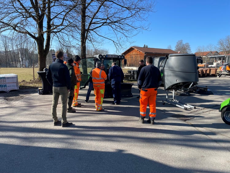 Teilnehmer in Arbeitskleidung versammeln sich um eine geöffnete Egholm Kommunalmaschine