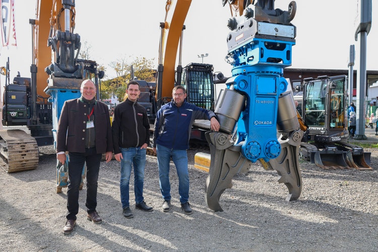 3 EDER Mitarbeiter stehen vor einem großen OKADA Greifarm auf der Kirchweihausstellung 2025 in Tuntenhausen