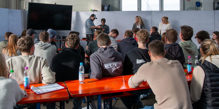 Auszubildende Sietzen an einem Tischen und hören einem Vortrag zu