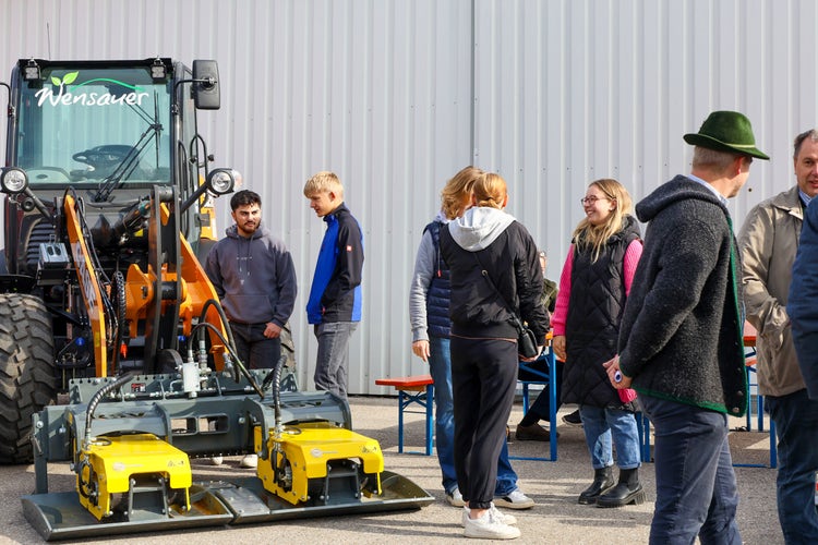 Leute bestaunen einen Schlepper mit Anbaugerät bei der Kirchweihausstellung 2025 in Tuntenhausen.