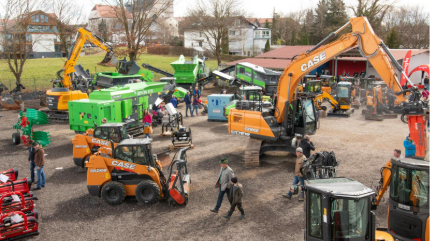 Baumaschienen wie Kettenbagger, Radlader, Raupenkompaktlader, Siebanlagen und Teleskoplader stehen auf einem rustikalen Untergrund bei der EDER Kirchweih Ausstellung